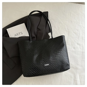 Gros plan du sac cabas noir tressé avec étiquette de mode et deux bretelles pour l'épaule