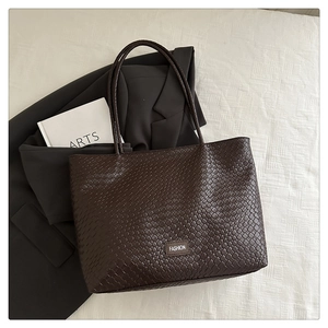 Détail de la texture tressée marron foncé et de l'étiquette Fashion sur le grand sac cabas
