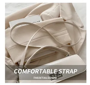 Detail of cream white handbag featuring a rotating metal lock and adjustable shoulder strap