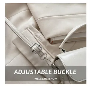 Detail view of adjustable silver buckle and glossy leather strap on white handbag