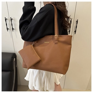 Detail of brown leather tote bag showing adjustable strap and small zipper pouch