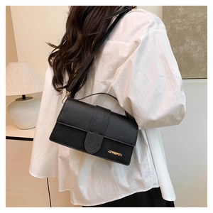 Model wearing black crossbody bag with gold logo and adjustable strap for women