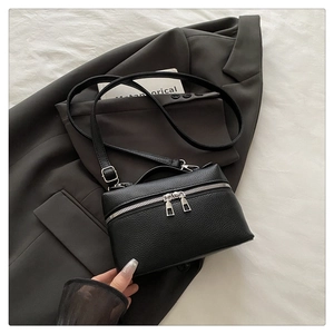 Détail d'un sac à main noir en cuir grainé avec fermeture éclair double et poignée