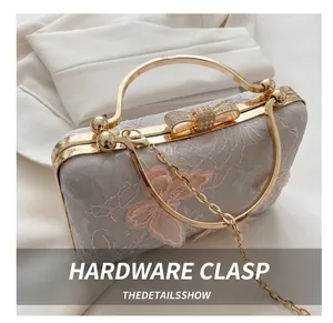 Detail of evening bag with golden hardware hooks and rhinestone bow clasp on lace