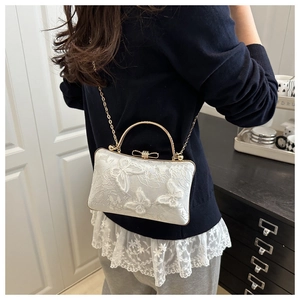 Detail of white lace evening bag with 3D butterfly appliques and gold bow clasp