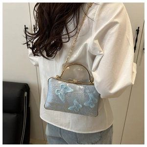 Detail of light blue evening bag with 3D butterfly embroidery and gold metal chain