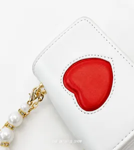 Detail of white leather heart bag showing exquisite pearl chain and rhinestone rings