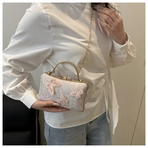 Detail of pink butterfly embroidery and rhinestone handle on a lace evening bag