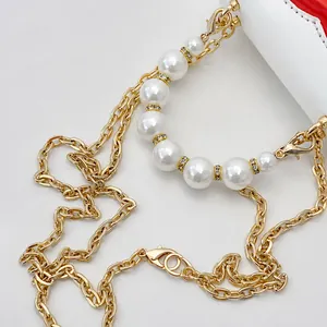 Detail of golden metal chain with white pearls and sparkling rhinestone spacers