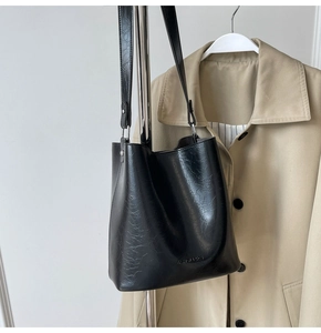 Détail du sac seau noir montrant la texture cuir vieilli et le logo de mode embossé