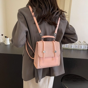 Pink minimalist backpack with straw texture detail and adjustable straps on a model