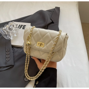 Close-up of beige quilted crossbody bag with gold chain and metal sphere buckle detail