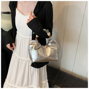 Detail of silver pleated bucket bag with vibrant acrylic beaded handle and drawstring