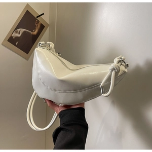 Detail of white glossy crescent bag featuring a unique knotted shoulder strap design