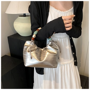 Detail of silver metallic bucket bag featuring multicolored beaded handle and drawstring top
