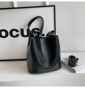 Détails du cuir craquelé noir et du logo argenté sur le sac à bandoulière