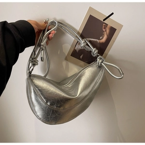 Close-up of a silver crescent bag with metallic pleats and knotted strap details