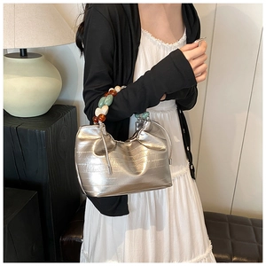 Detail of silver pleated bucket bag with colorful beaded handle and drawstring accents