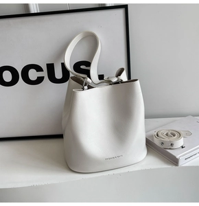 Détail du sac seau minimaliste blanc avec texture craquelée et lettrage doré élégant