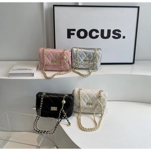 Detail of four quilted mini bags in pink silver black and white with gold ball chains