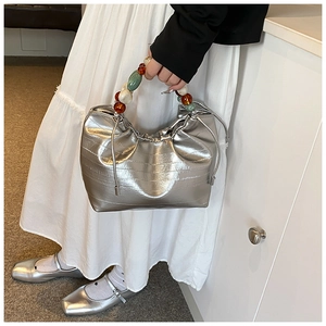 Silver metallic bucket bag with colorful beaded handle and drawstring detail