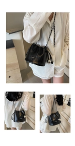 Close-up of black glossy leather bucket bag with silver chain strap and metal ball detail