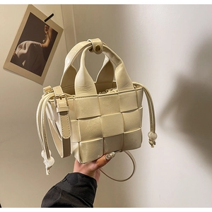 Détail du sac seau tissé blanc cassé avec motifs floraux et cordon de serrage