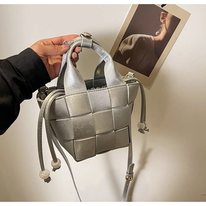 Détail du sac seau tressé argenté avec fermeture à cordon et poignée ronde