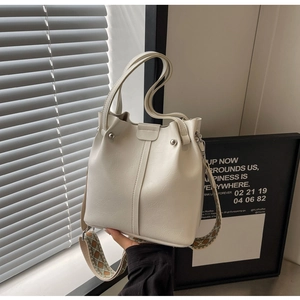 Detail der cremefarbenen Beuteltasche aus strukturiertem Leder mit gemustertem Gurt