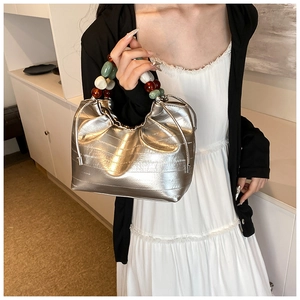 Detail of silver metallic bucket bag with colorful beaded handle and drawstring closure