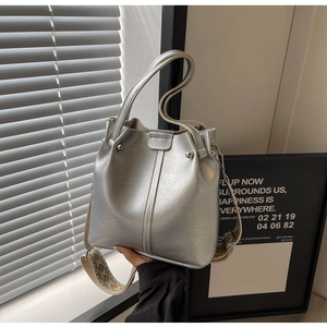 Detail der silbernen Bucket Bag mit Riss-Textur und gemustertem breitem Schultergurt