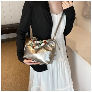 Detail of silver metallic bucket bag with colorful beaded handle and wrinkled texture