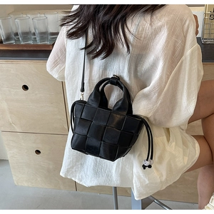 Détail d'un sac seau tissé noir avec motifs carrés et perles sur le cordon de serrage