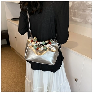 Detail of silver pleated bucket bag with decorative colorful pebble bead handle