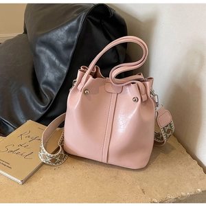 Rosa Eimertasche mit dekorativem breitem Gurt und Silberbeschlägen auf Stein