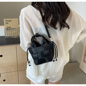 Détail du sac seau en cuir tressé noir avec fermeture à cordon et perles