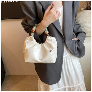 Detail of white crocodile texture bucket bag with colorful beaded handle and logo