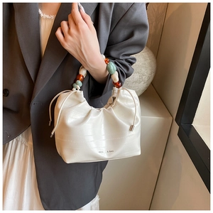 Detailed view of cream pleated bucket bag with decorative colorful acrylic beaded handle