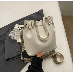 Detail der weißen Beuteltasche mit Lederstruktur und gewebtem Schultergurt im Boho-Stil