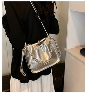 Detail of silver metallic drawstring bucket bag with pleated design and beaded chain strap