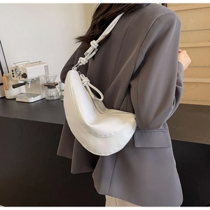 Close-up of a white minimalist hobo bag with knot strap detail and silver zipper closure