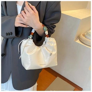 Detail of white pleated bucket bag with unique beaded handle and elegant PU leather texture