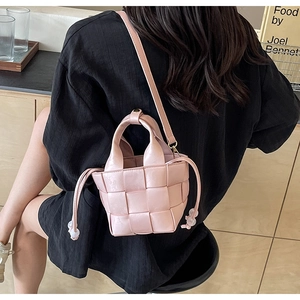 Détail d'un sac seau tressé rose avec cordon de serrage et perles transparentes