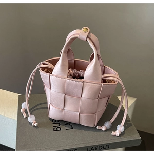 Gros plan du sac seau rose tressé avec cordon de serrage et texture en similicuir