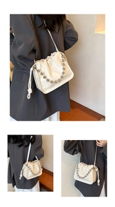 Close-up of drawstring bucket bag with shiny patent leather and metal bead chain detail