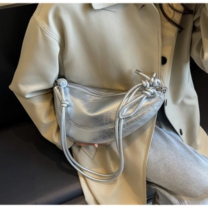 Detail of silver crescent bag with wrinkled metallic texture and knotted straps
