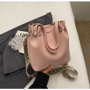 Detailansicht der rosa Lederbeuteltasche mit Textur und ethnisch gemustertem Gurt