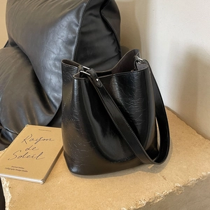 Sac seau noir chic avec texture en cuir craquelé vintage et large bandoulière