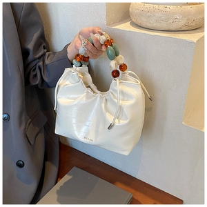Detail of white PU leather bag featuring unique agate-style beaded handle and brand logo