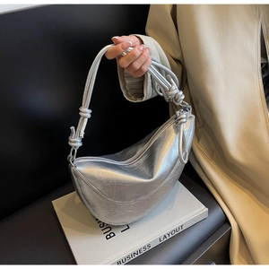 Detail of silver croissant bag with crinkle texture and stylish knotted strap design
